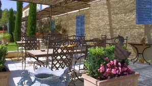 An outdoor patio with metal furniture, a stone wall, and potted plants.