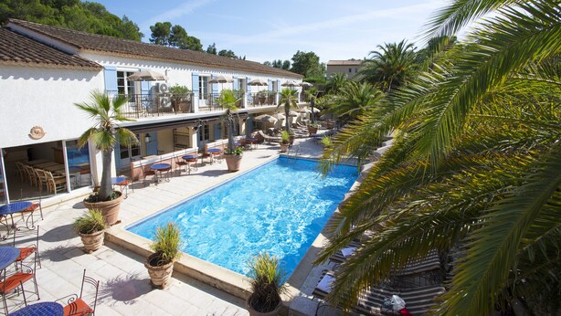 A pool area with a clear blue pool, surrounded by potted plants and outdoor furniture.