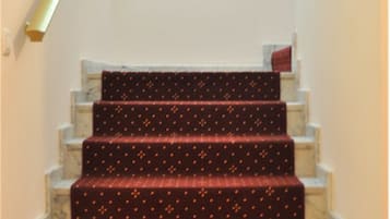 Una escalera con alfombra roja y barandilla dorada.
