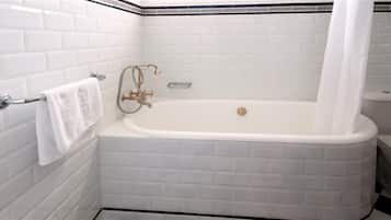 A bathroom with a white bathtub, a towel rack, and a showerhead.