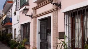 A pink hotel with balconies, potted plants, and a sign indicating it is a central hotel. - Hotel Central (Marbella)