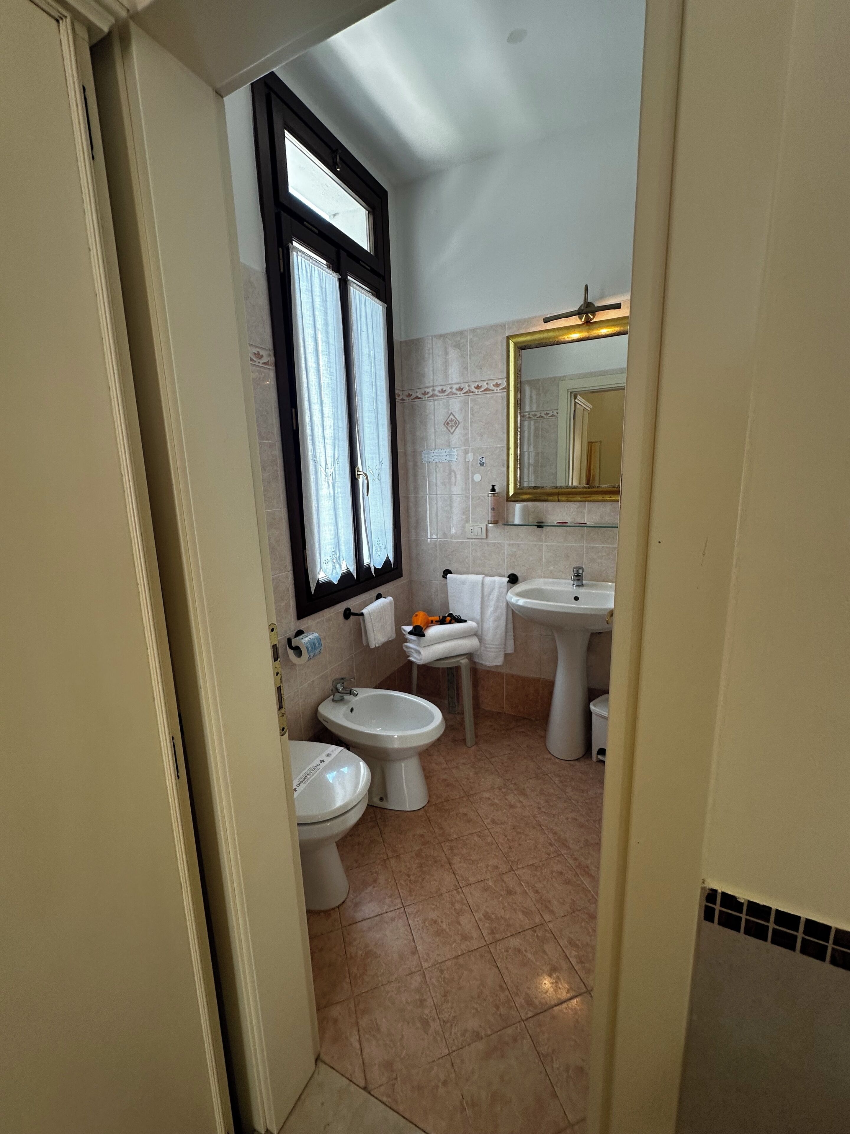 Une salle de bain avec une fenêtre, deux lavabos, deux toilettes et un miroir.