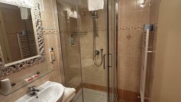 Une salle de bain avec une douche à parois de verre, un lavabo avec un miroir et un porte-serviettes.