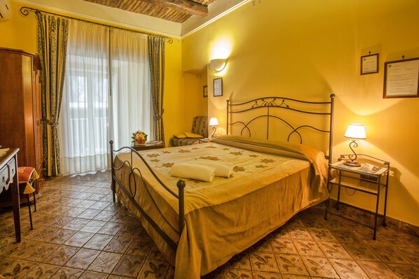 Una habitación de hotel con una cama, una mesita de noche, una silla, un escritorio y una ventana con cortinas.
