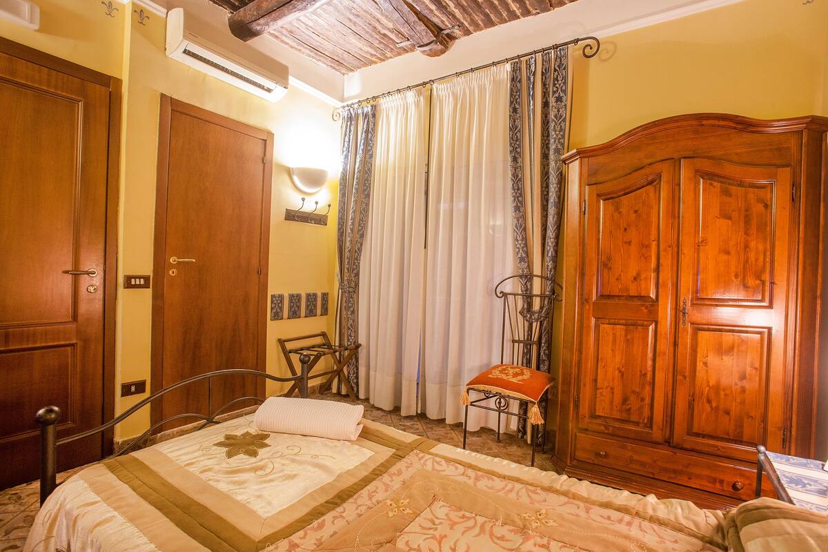 A bedroom with a bed, wooden wardrobe, and a chair.
