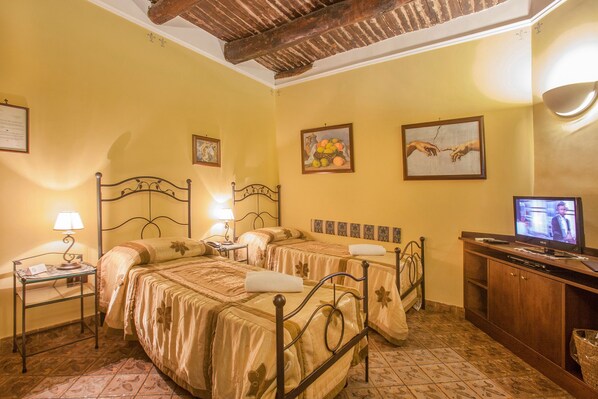 A hotel room with two beds, a television, a desk with a lamp, and artwork on the walls. - B&B L'Alloggio dei Vassalli (Naples)