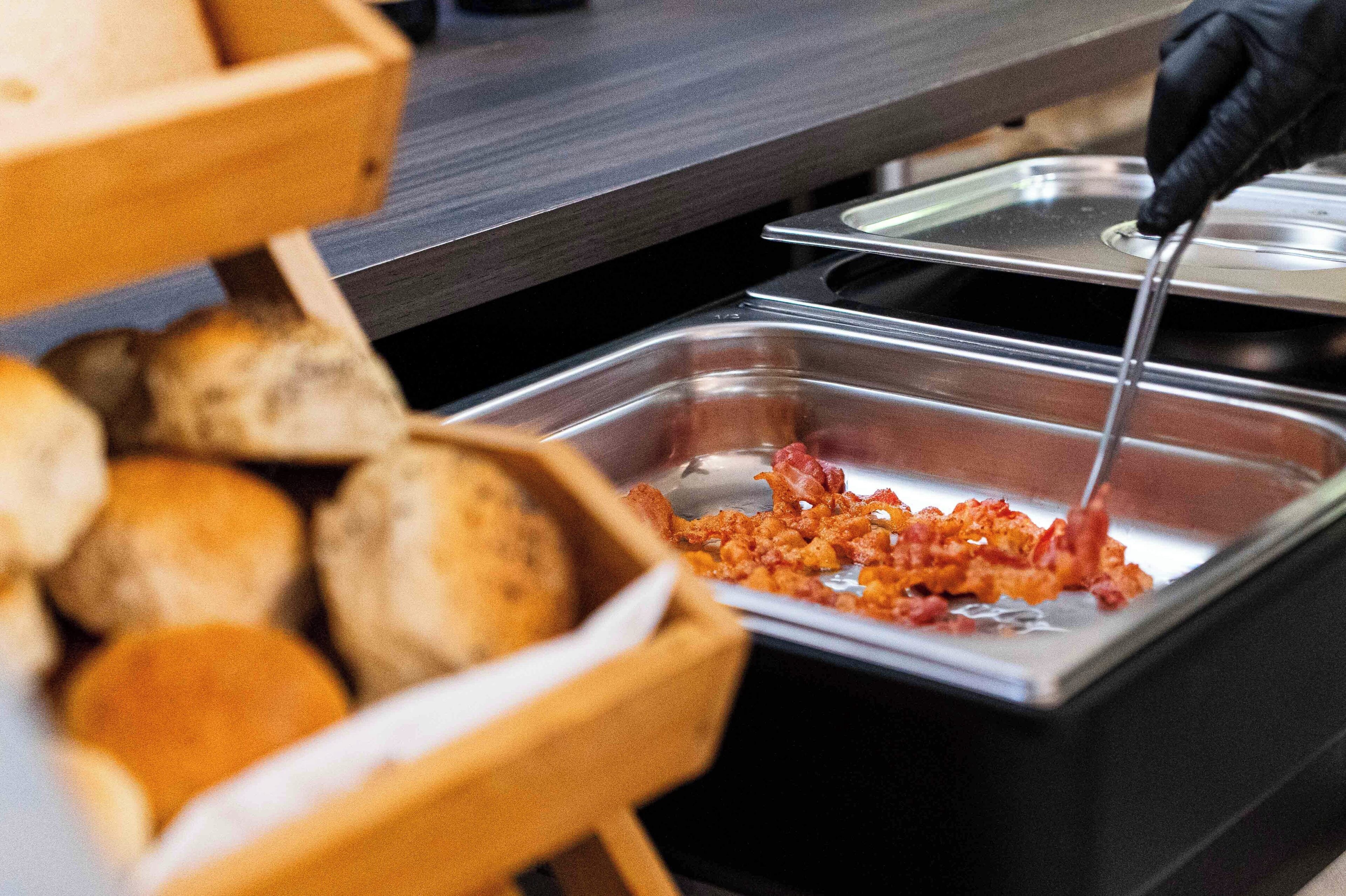 A buffet setup with bread and a dish containing a red sauce.