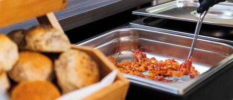 A buffet setup with bread and a dish containing a red sauce.
