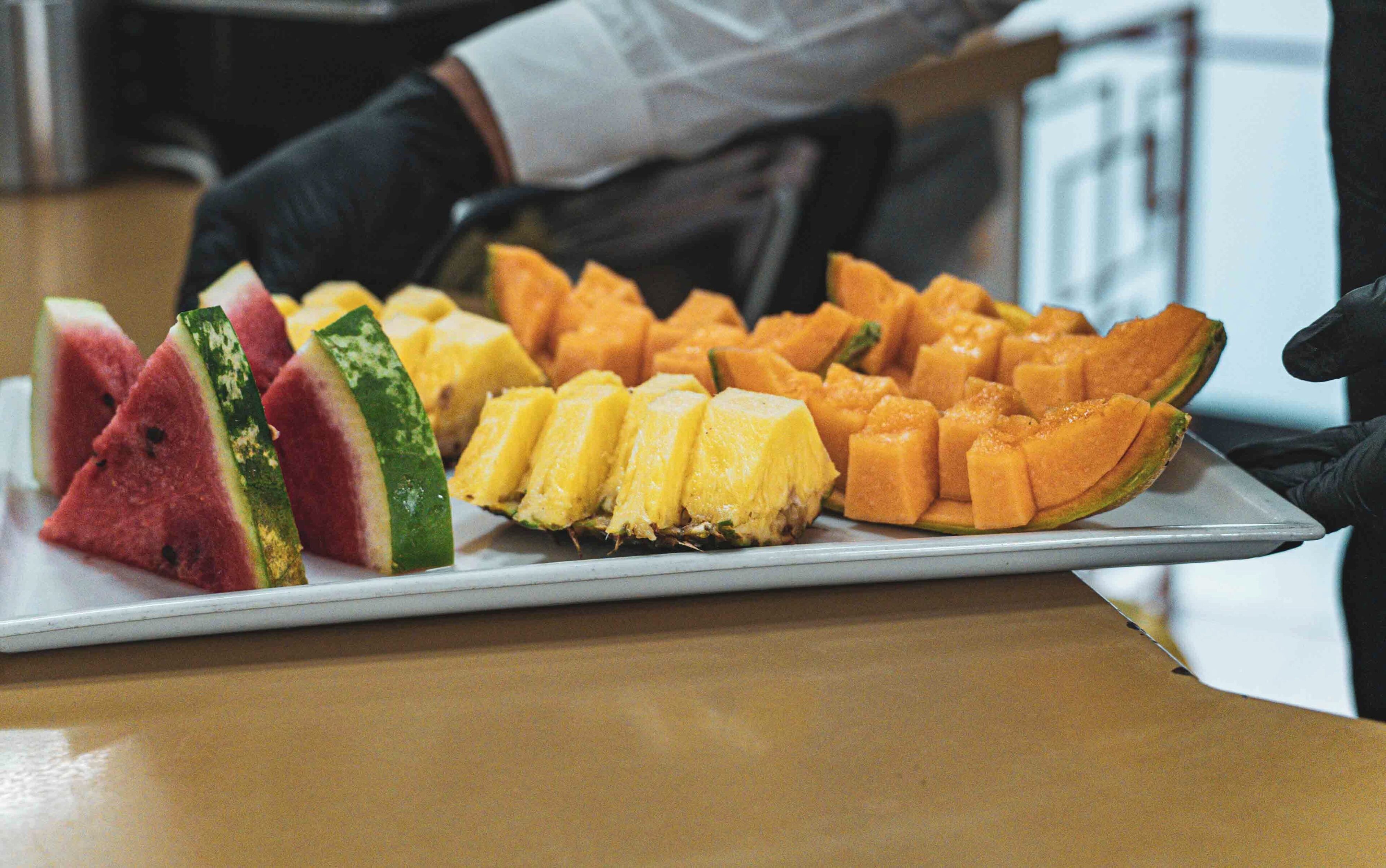 A tray of sliced fruits including watermelon, pineapple, and mango.