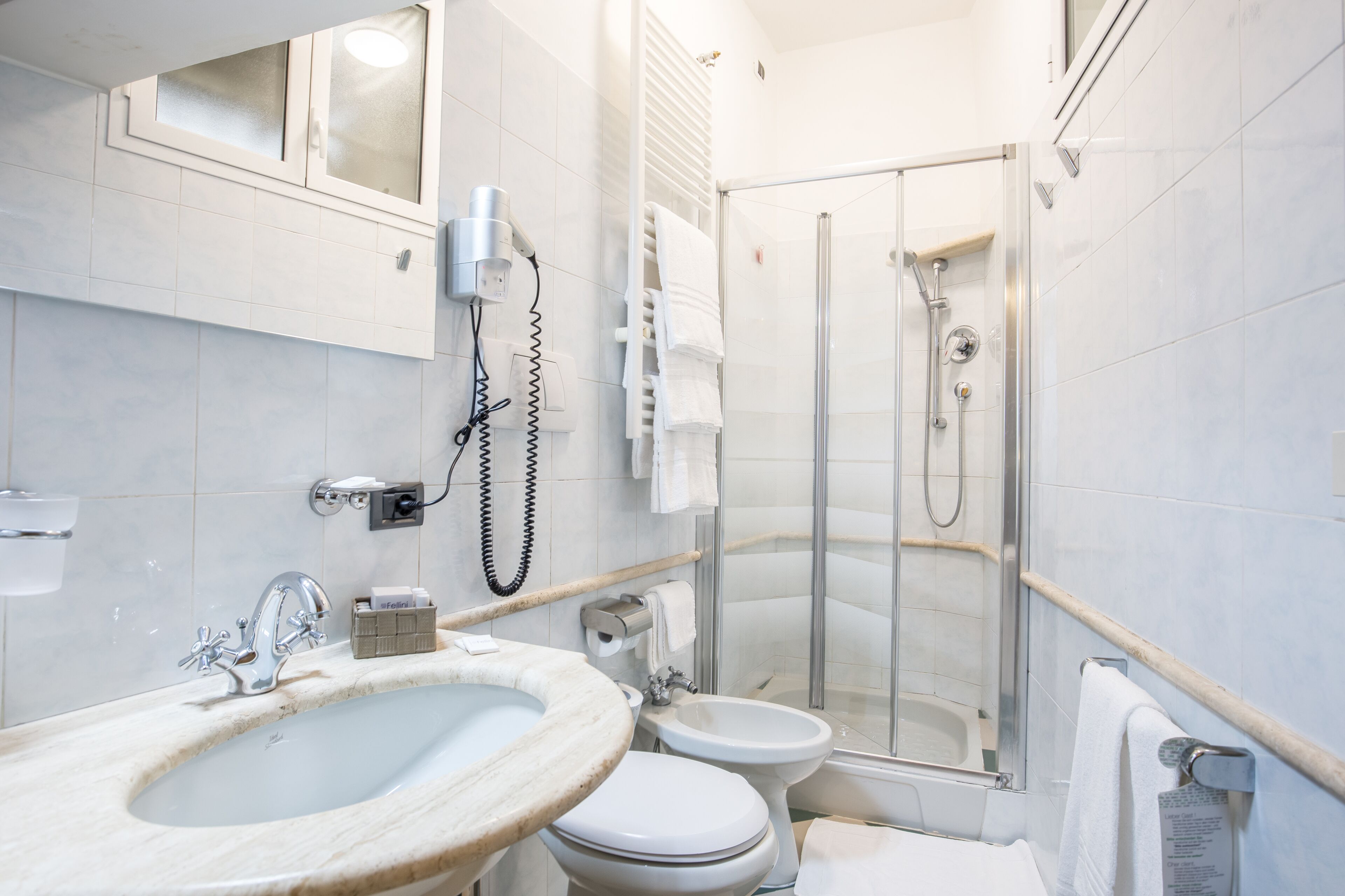 Un baño con lavabo, inodoro, bidé y cabina de ducha con mampara de vidrio.