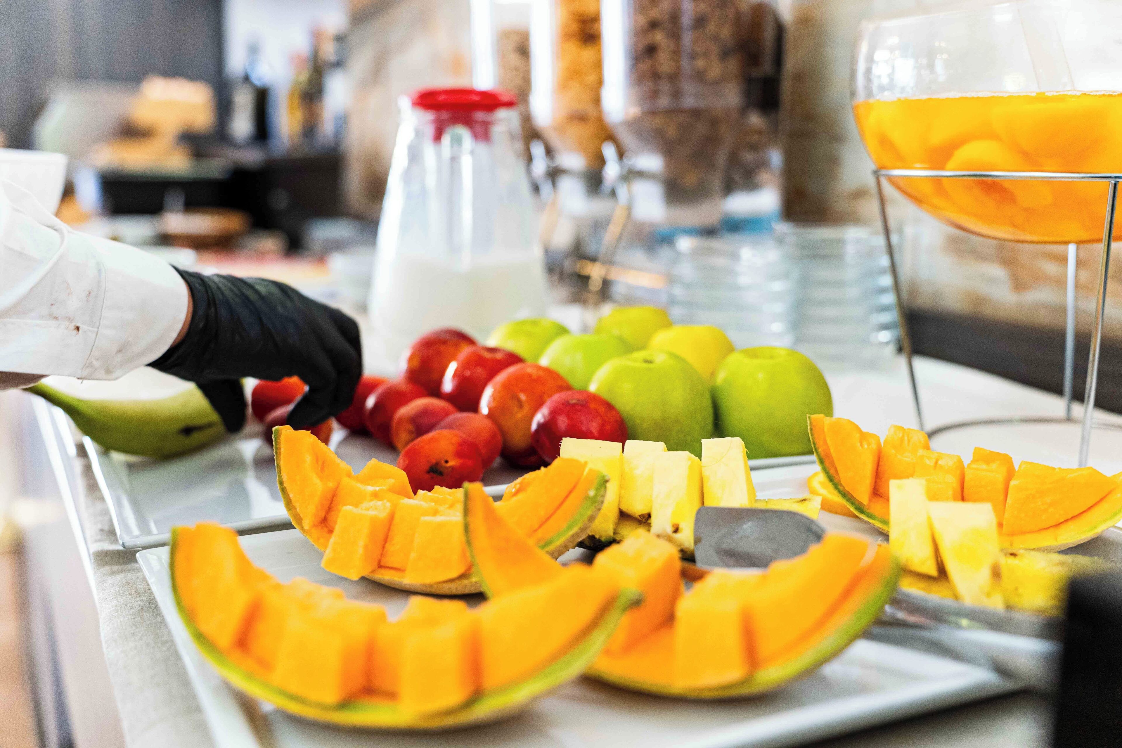 A fruit platter with various fruits and a glass of orange juice.