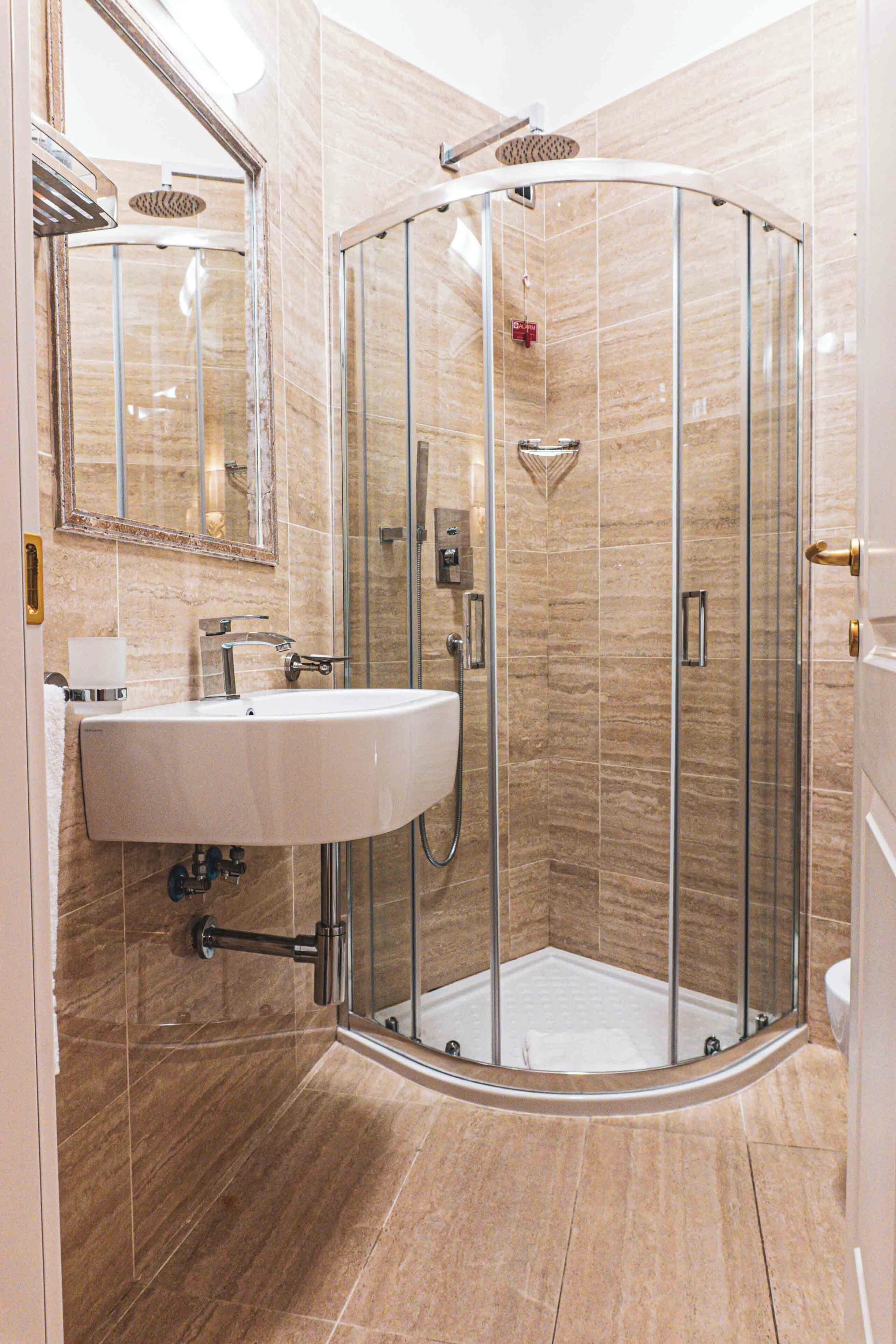 A modern bathroom with a glass-enclosed shower, a white sink, and a mirror.