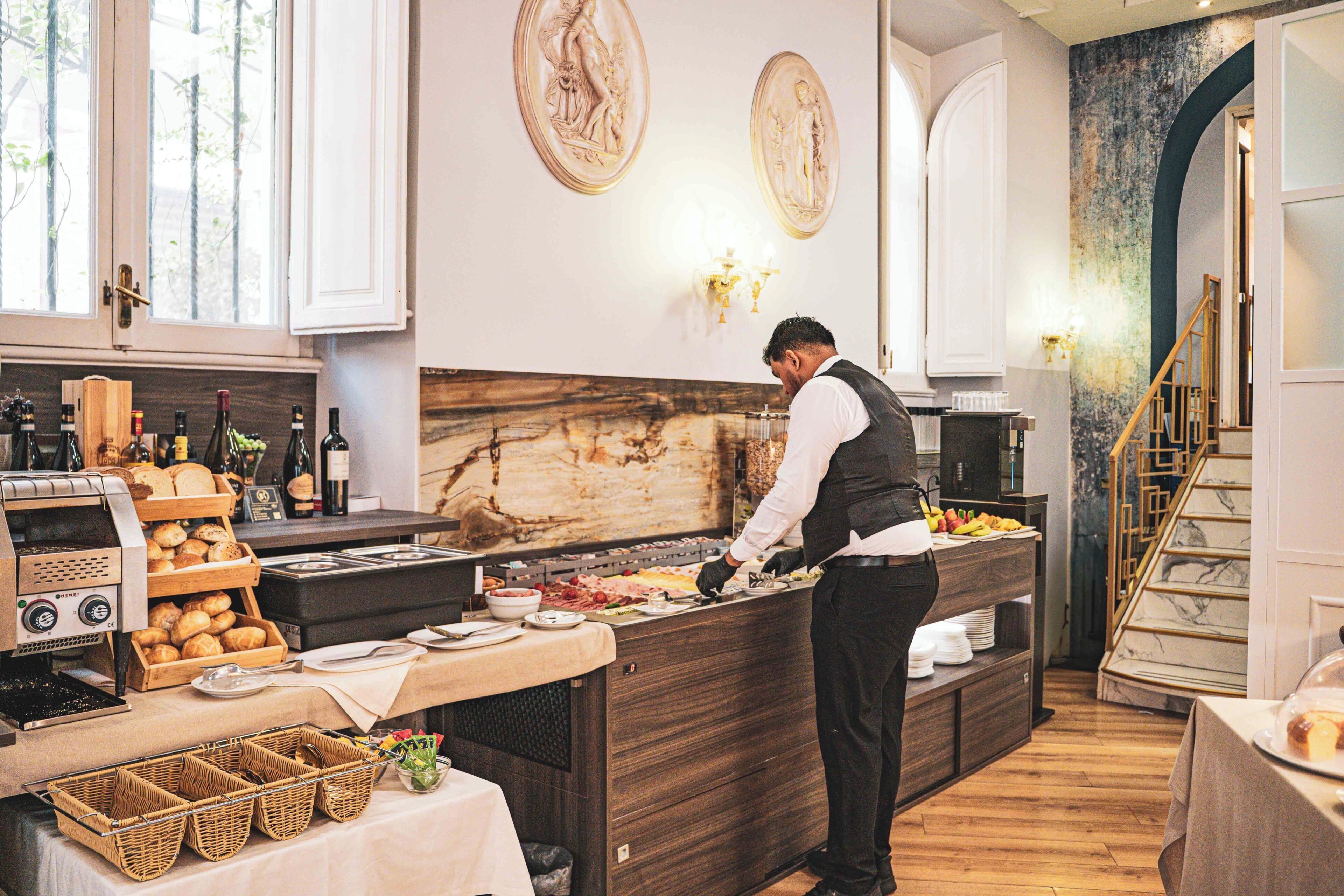 A breakfast buffet setup with a coffee machine, bread, and wine bottles.