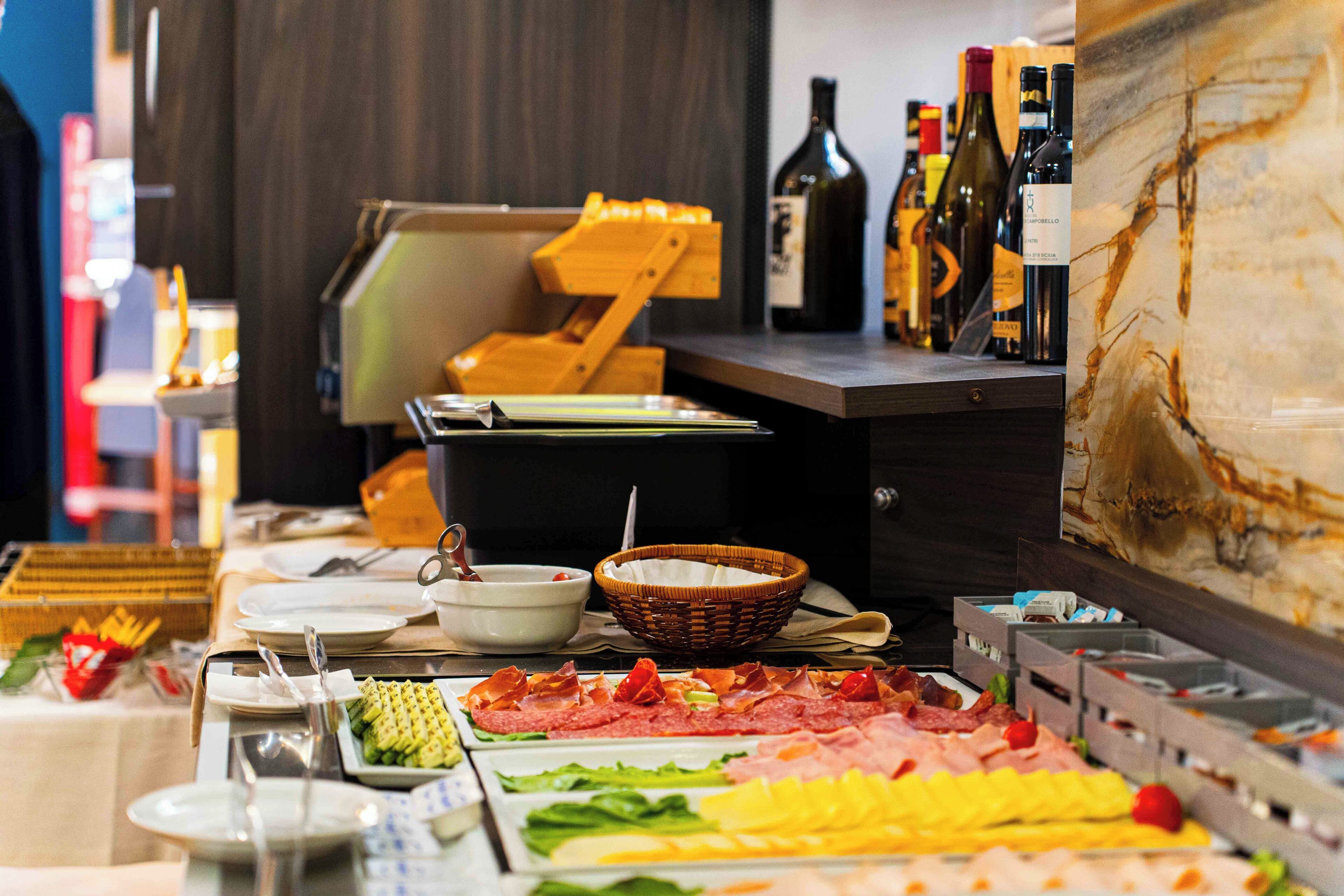 A buffet setup with various food items, a wine selection, and a wooden chair.