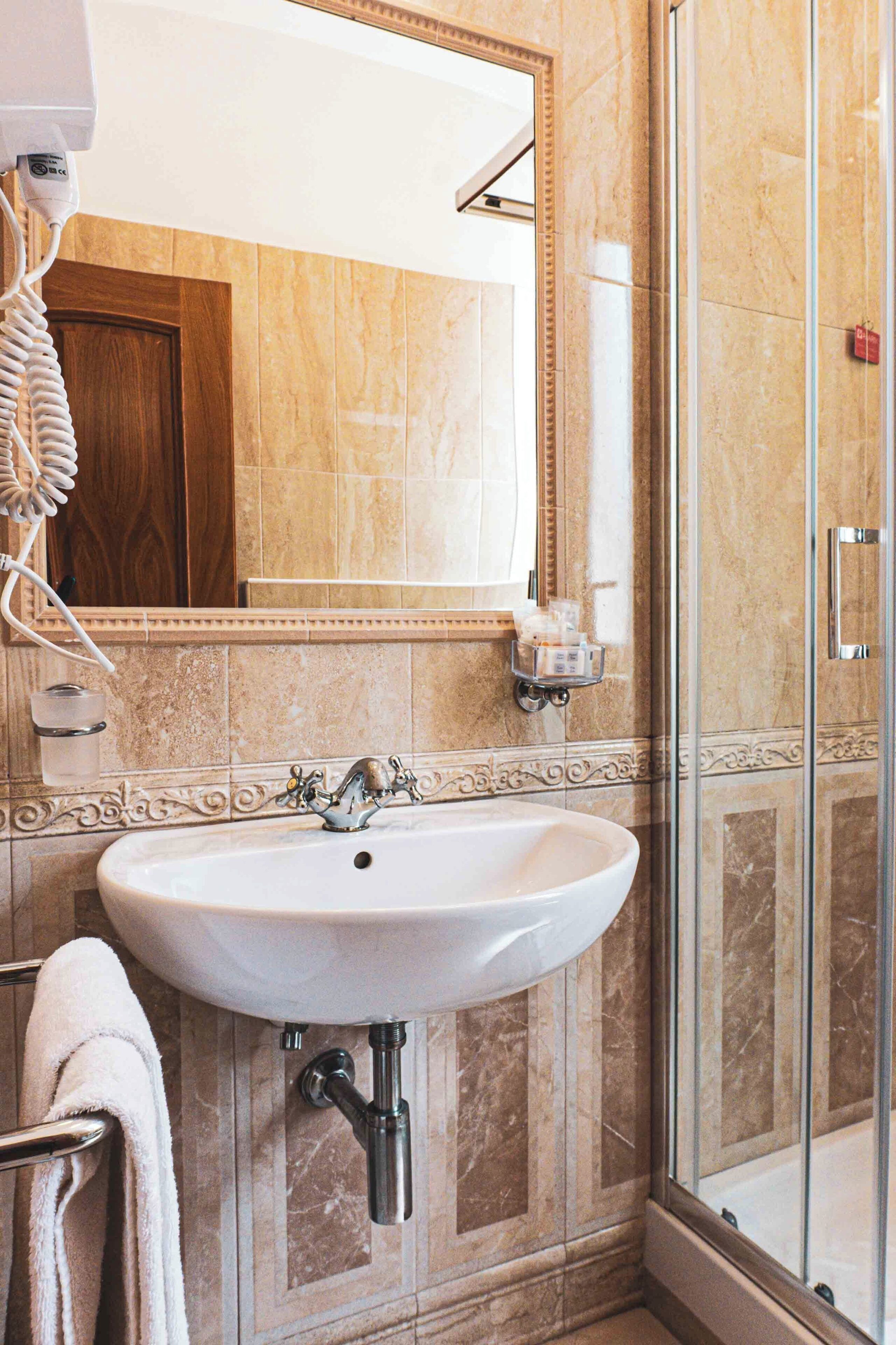 A bathroom with a sink, mirror, towel rack, and shower.