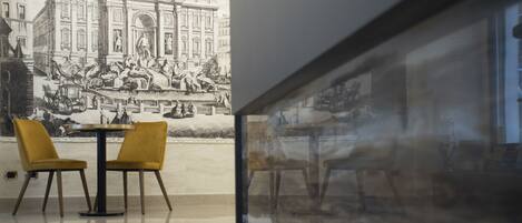 A dining area with a mural of a historical building, two yellow chairs, and a round table.