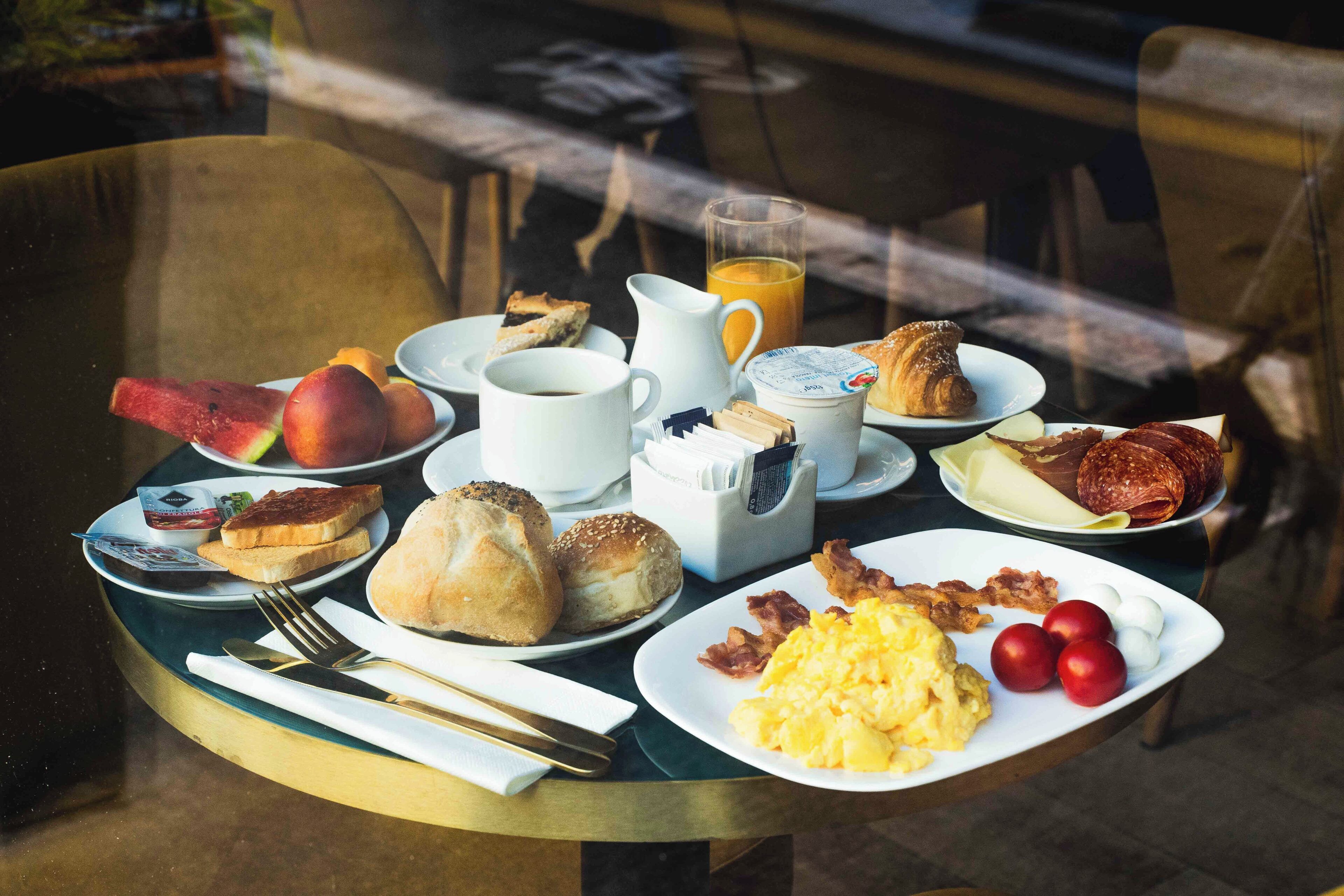 A breakfast table with various food items and a glass of orange juice.