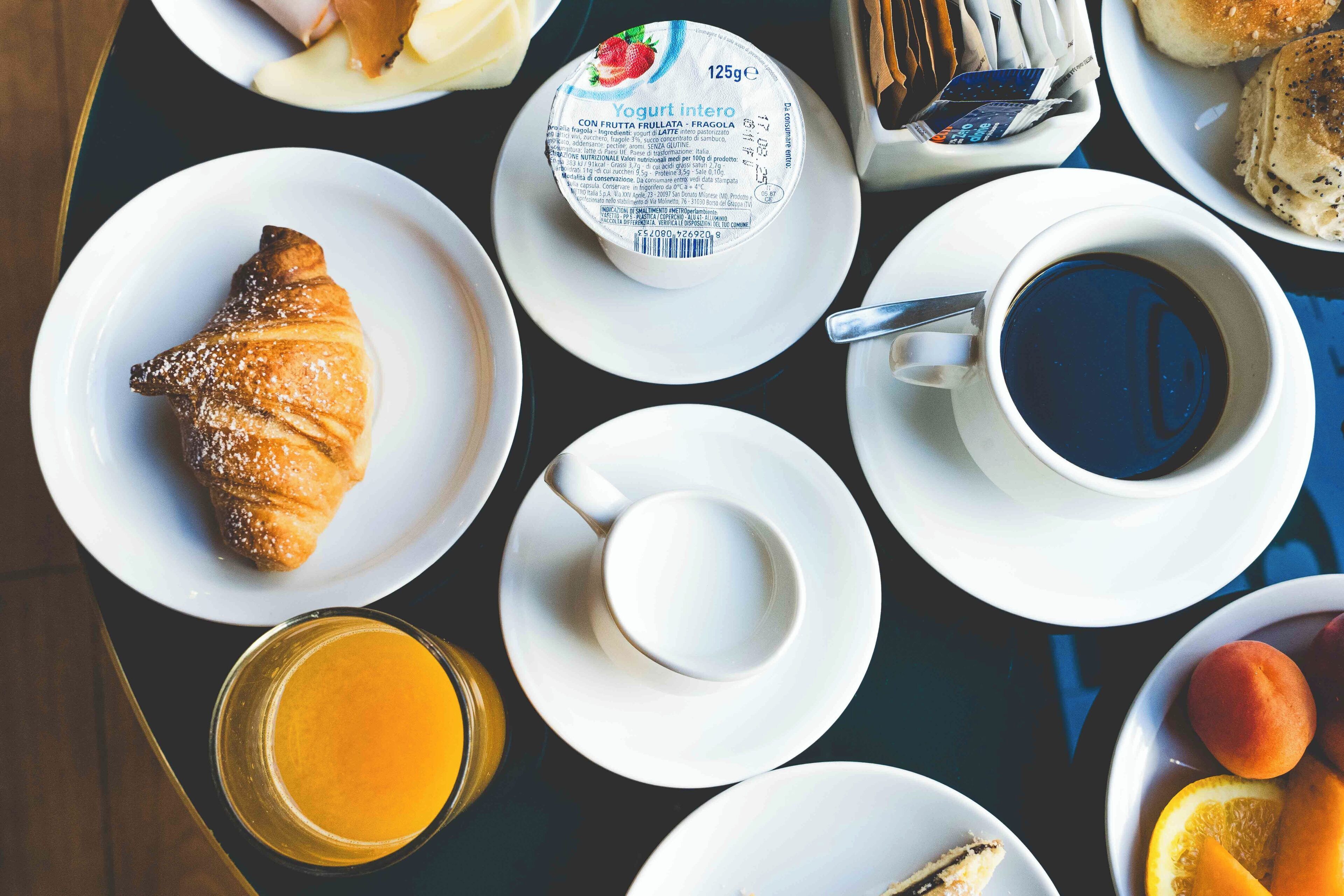 A breakfast setting with croissants, yogurt, coffee, and fruit.