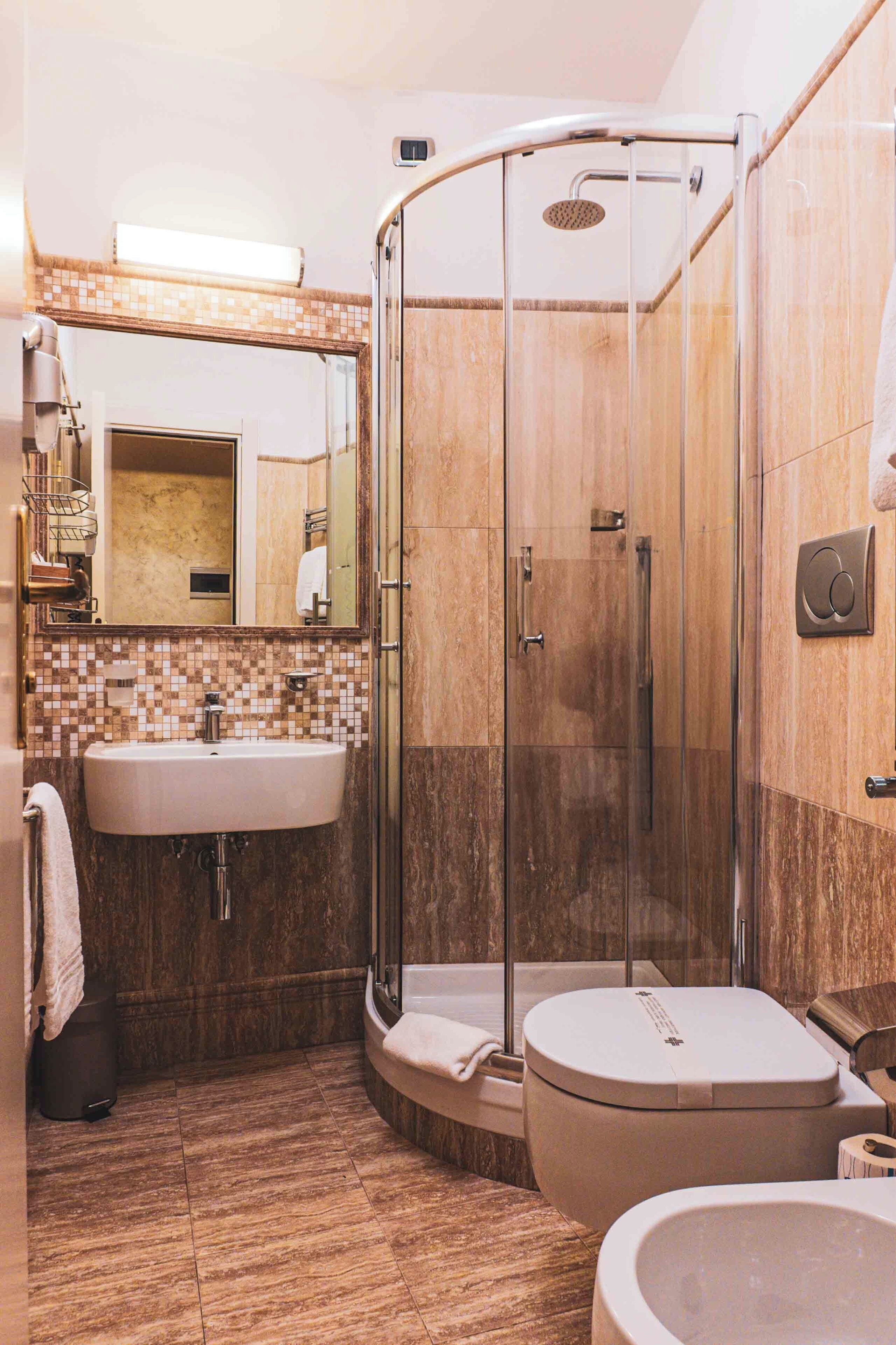 A modern bathroom with a glass-enclosed shower, a sink, and a toilet.