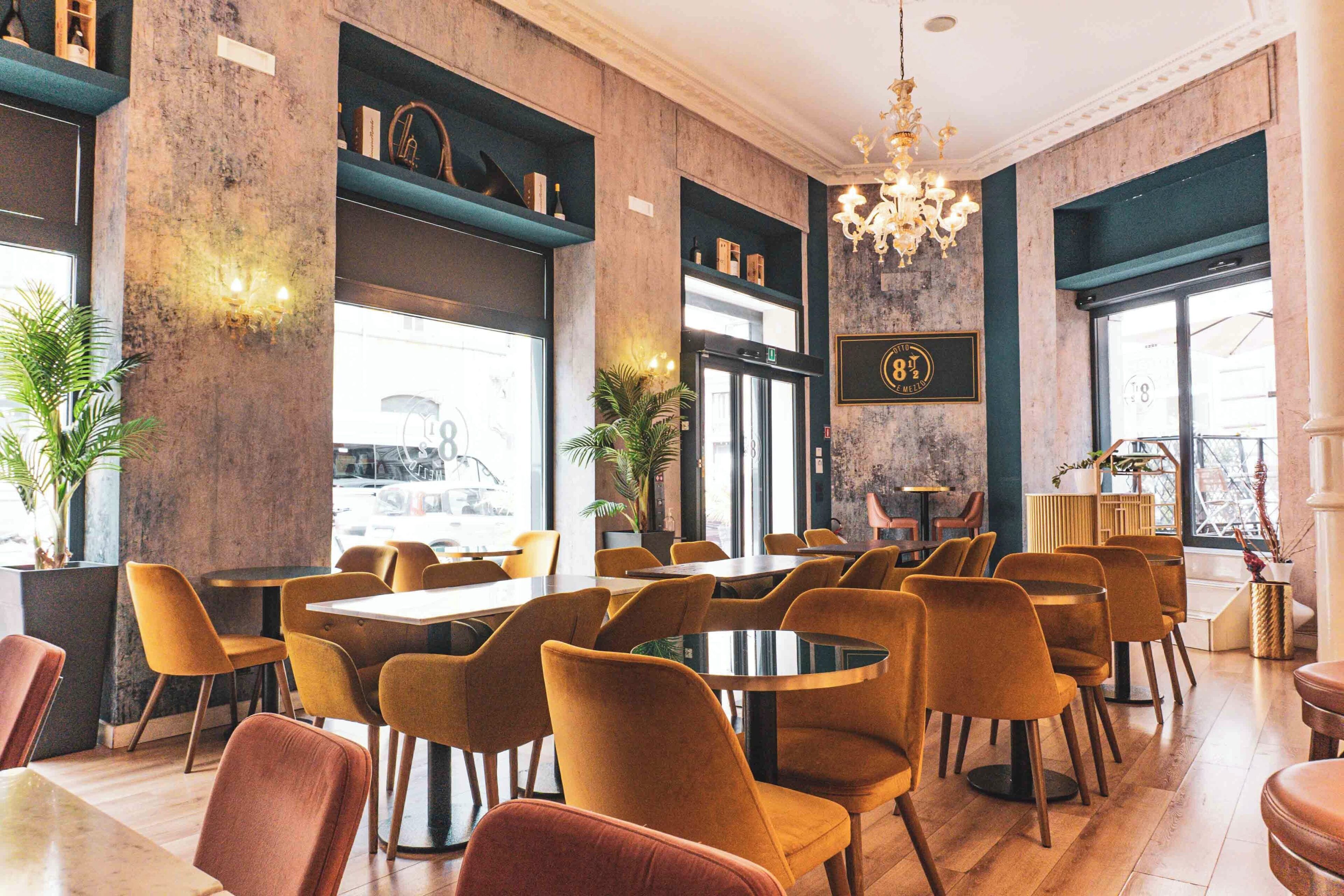 Un restaurant avec des tables et des chaises rondes, un lustre et une vue sur la rue.
