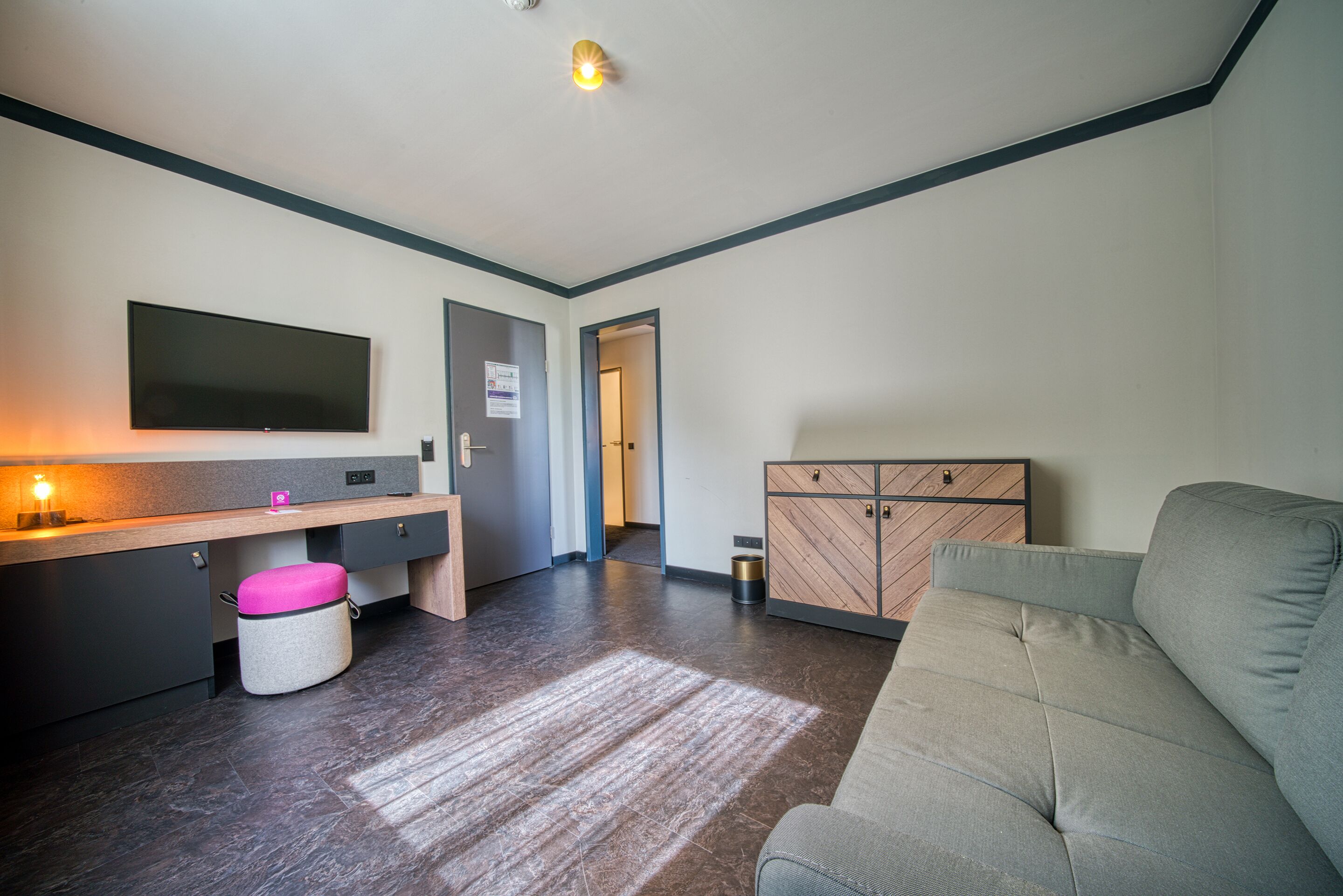Ein modernes Wohnzimmer mit Flachbildfernseher, einer Couch, einem Holzschrank und einem kleinen Hocker.