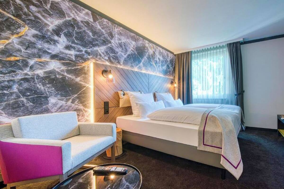 Ein Hotelzimmer mit einem Bett, einem Sessel, einem Fernseher und einer Marmorwand.