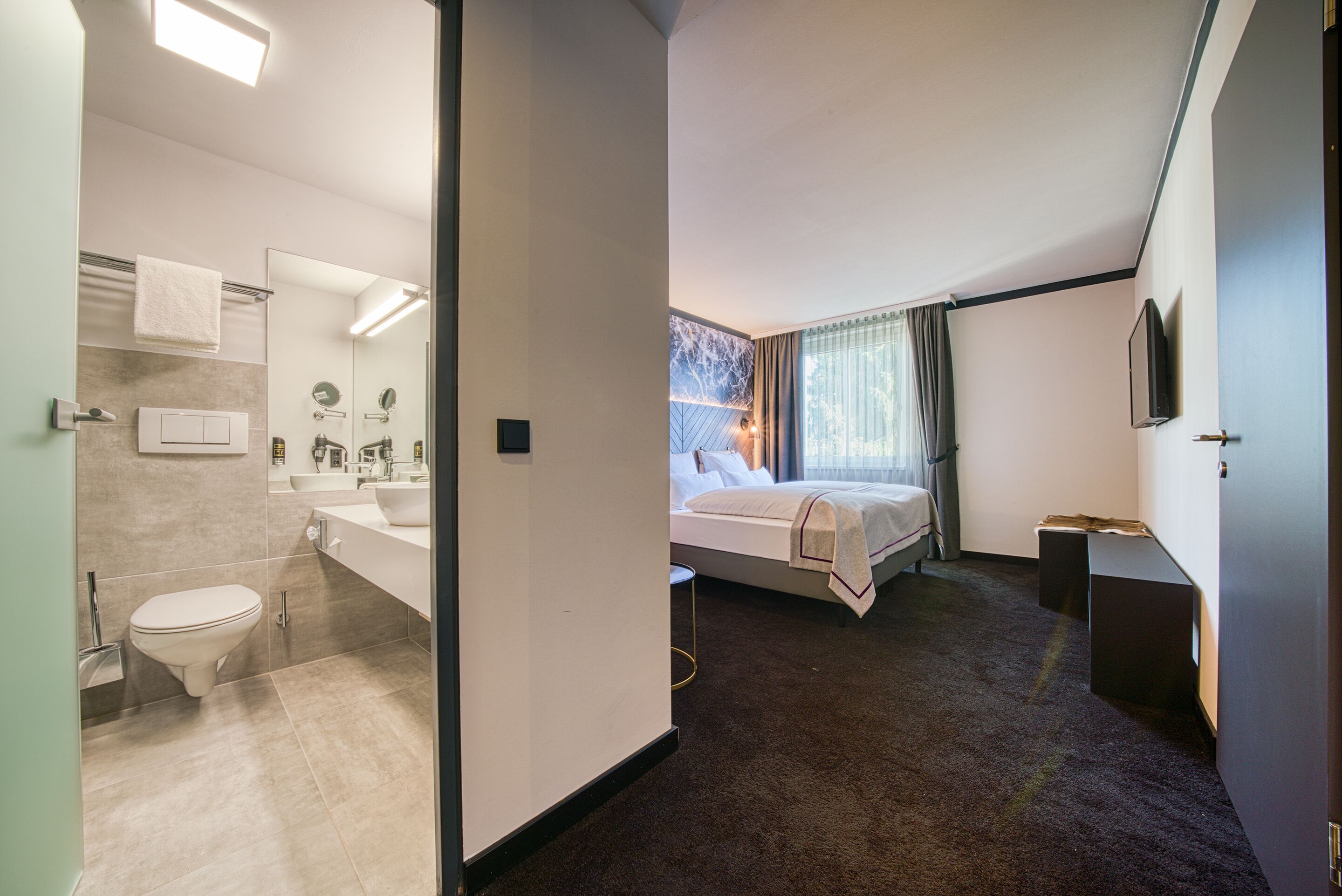 Una habitación de hotel moderna con baño, cama y televisión.