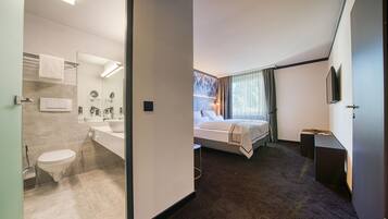 Una habitación de hotel moderna con baño, cama y televisión.