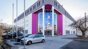 Ein modernes Gebäude mit einer gebogenen Fassade, großen Fenstern und einem Schild mit der Aufschrift 'Four Side Hotels'.