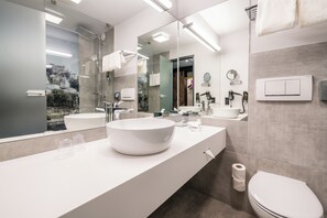 Ein modernes Badezimmer mit einem großen Spiegel, zwei Waschbecken, einer Toilette und einer Dusche.