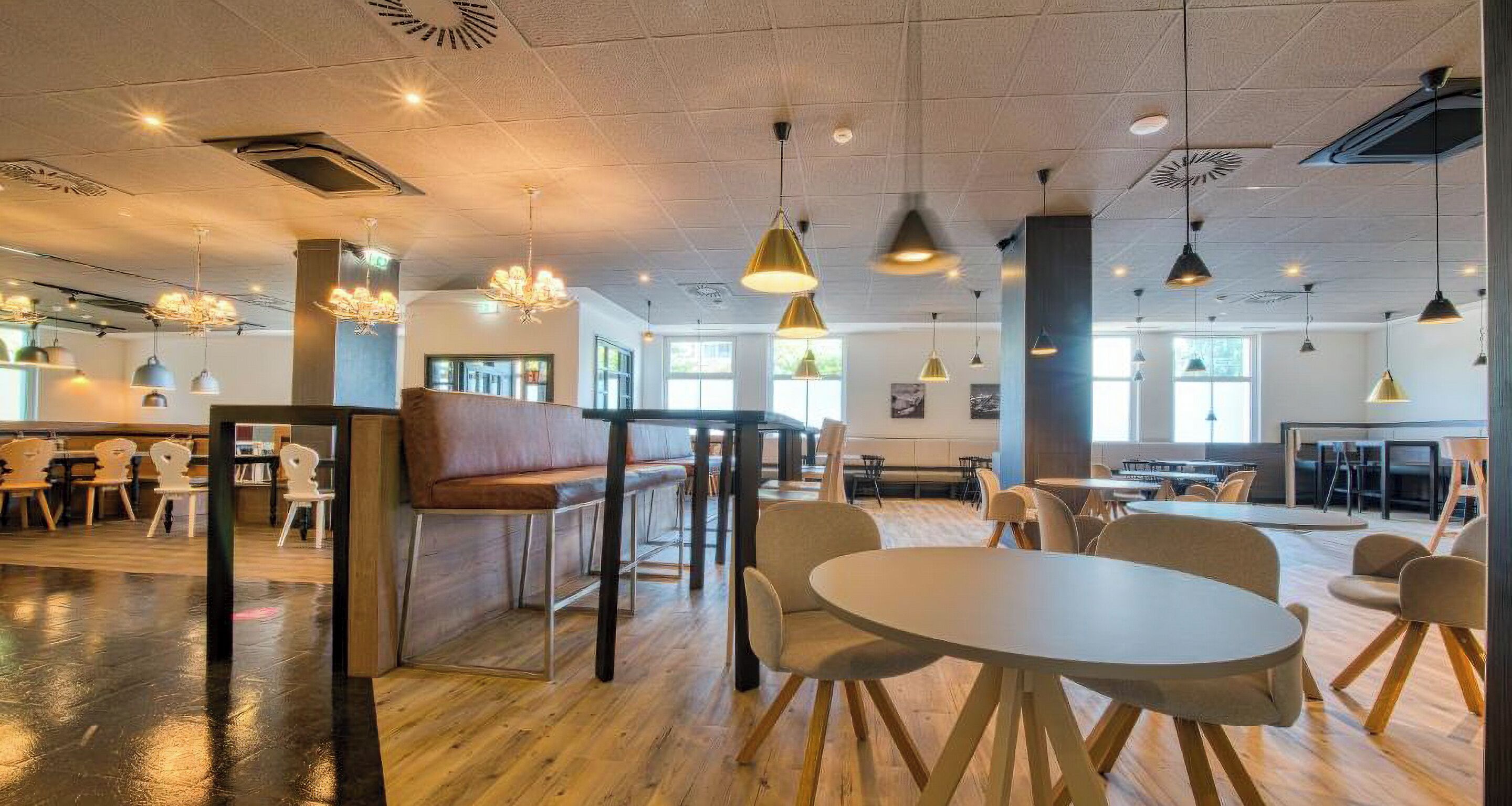 A spacious indoor area with multiple seating arrangements, including tables and chairs, and a central seating area with a bench.