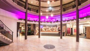 A multi-level hotel lobby with a reception desk, a staircase, and a modern design. - PLAZA INN Salzburg Messe  (Salzburg)