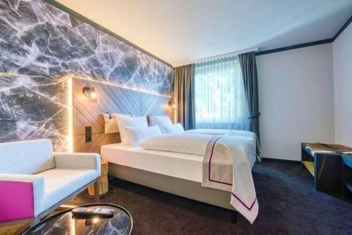 Ein Hotelzimmer mit Bett, einer Sitzecke, einem Nachttisch und einer Marmorwand.