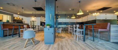 Un interior moderno con piso de madera, asientos de bar e iluminación colgante.
