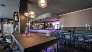 A modern bar area with a marble countertop, bar stools, pendant lighting, and a purple-lit bar counter. - PLAZA INN Salzburg Messe  (Salzburg)