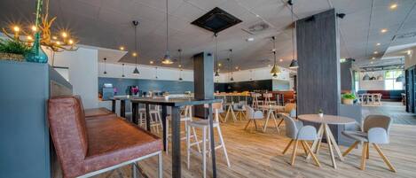 Un restaurante moderno con suelo de madera, varias zonas de estar, iluminación colgante y una barra.