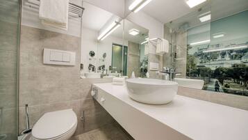 Un baño moderno con un espejo grande, un lavabo blanco y un inodoro.