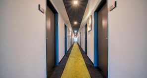 A hotel corridor with a yellow carpet, blue doors, and numbered room signs. - PLAZA INN Salzburg Messe  (Salzburg)