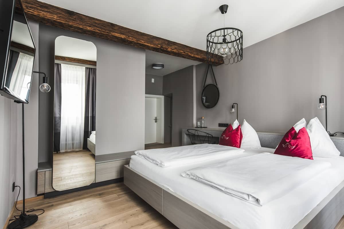 Habitació d'hotel moderna amb un llit gran, una taula de treball i un mirall.