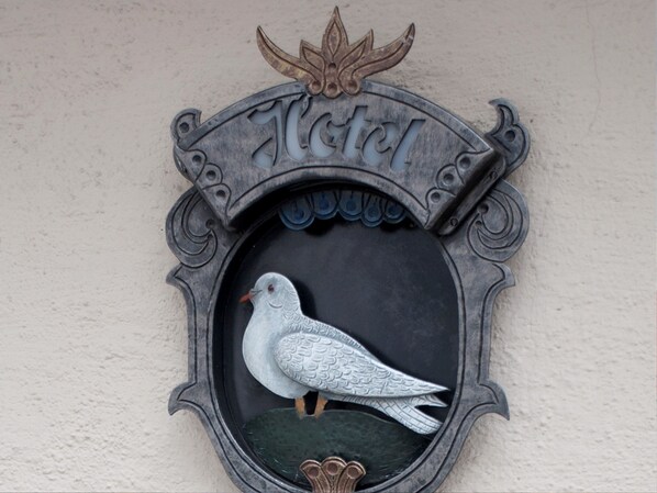 Un letrero metálico decorativo con un pájaro y la palabra 'Hotel' grabada.