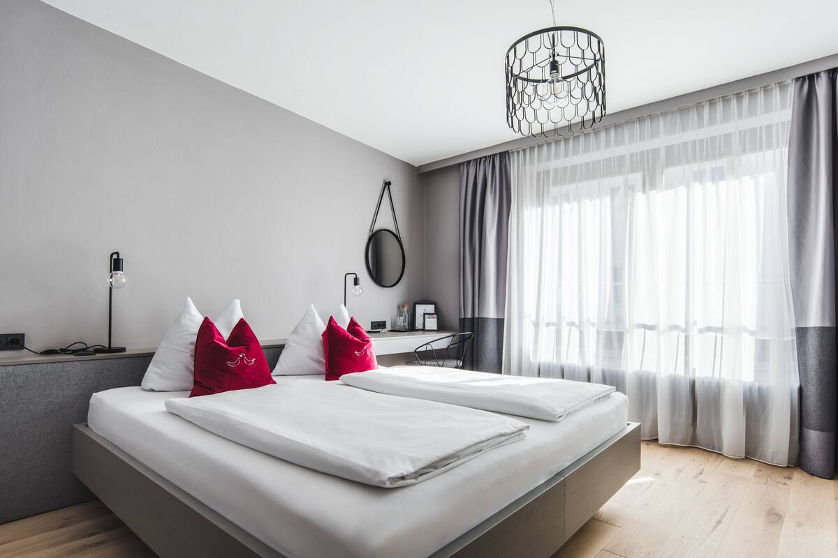 Una habitació d'hotel moderna amb un llit gran, un escriptori i una cadira.