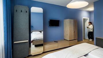 Une chambre à coucher moderne avec un lit, une armoire, un téléviseur et un miroir.
