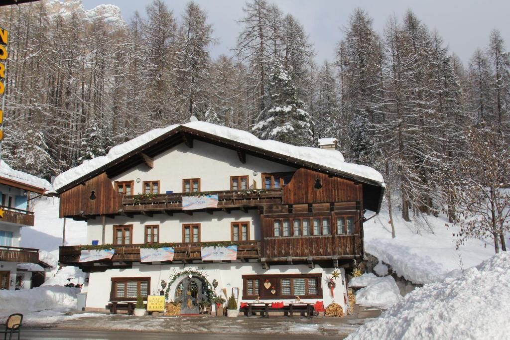 Un edificio de estilo chalé tradicional con varios balcones, rodeado de árboles cubiertos de nieve.