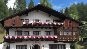 Un edifici de tipus xalet tradicional amb un balcó decorat amb flors, un rètol que diu "Alberta" i una entrada acollidora.