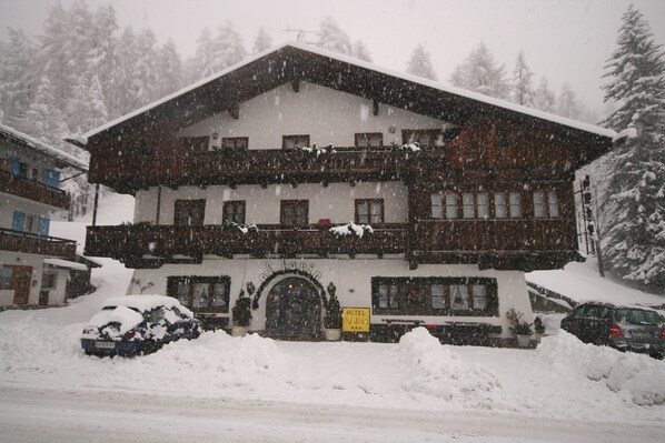 A hotel with a traditional Alpine architectural style, featuring a symmetrical facade, wooden balconies, and a central entrance. - Hotel Al Larin (Cortina d'Ampezzo)