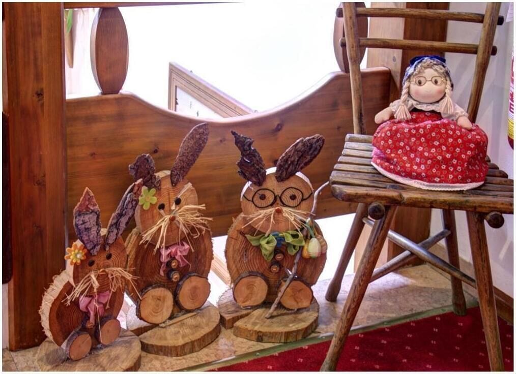 Una silla de madera con un peluche y dos figuras de conejos de madera.