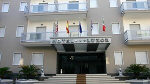 Entrada de hotel com uma escadaria dupla, várias varandas e bandeiras de diferentes países.