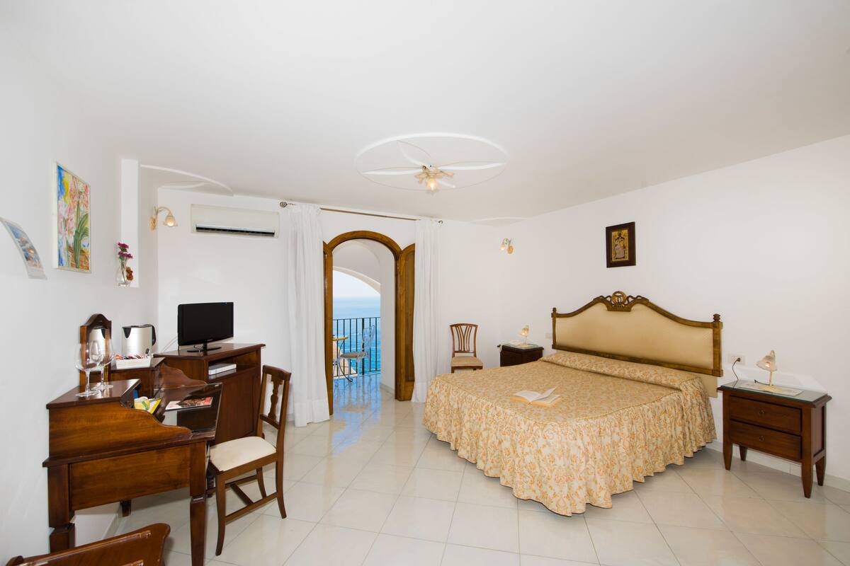 Une chambre avec un lit, un bureau, une chaise et une vue sur la mer.