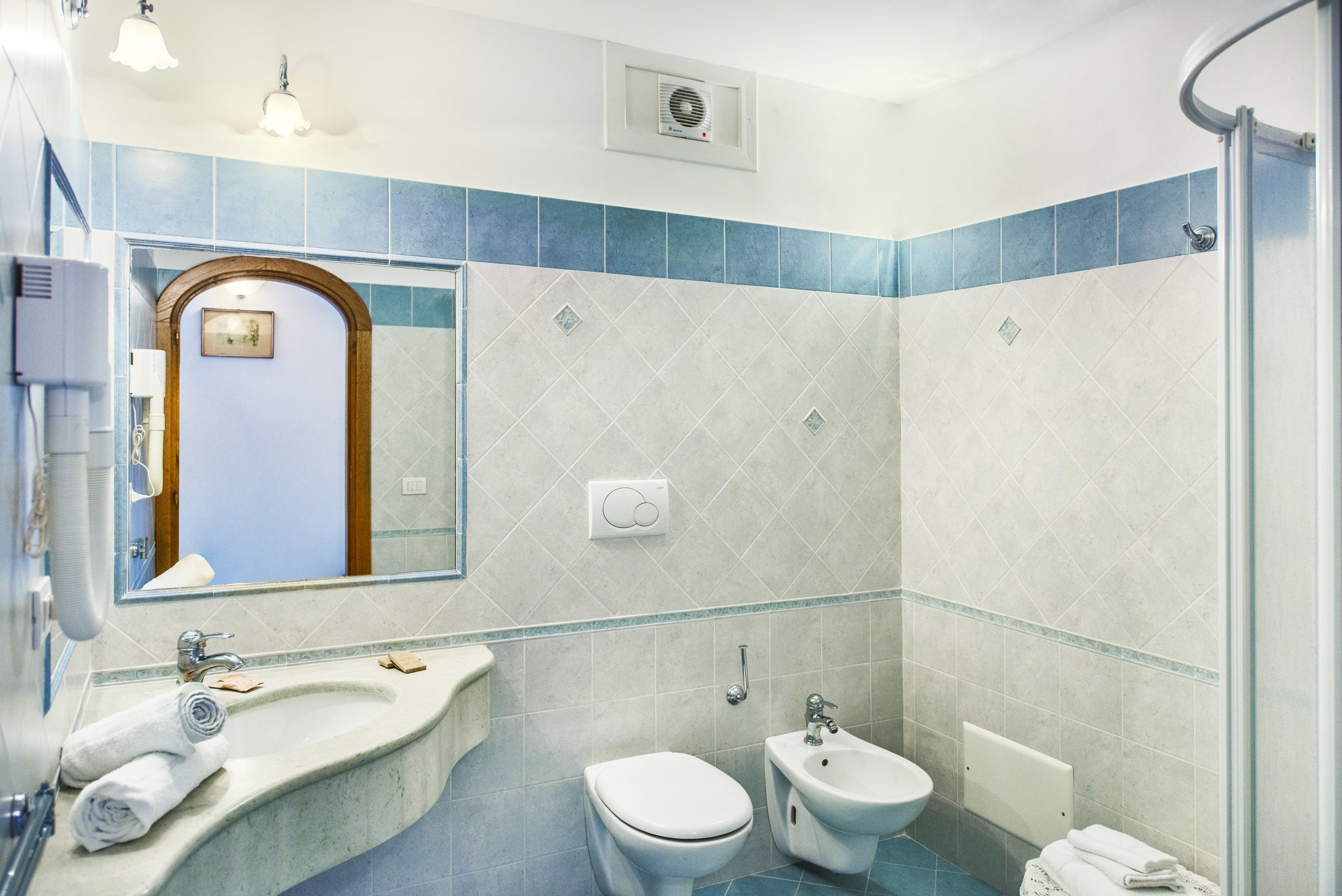 A bathroom with a sink, toilet, bidet, and a shower area.