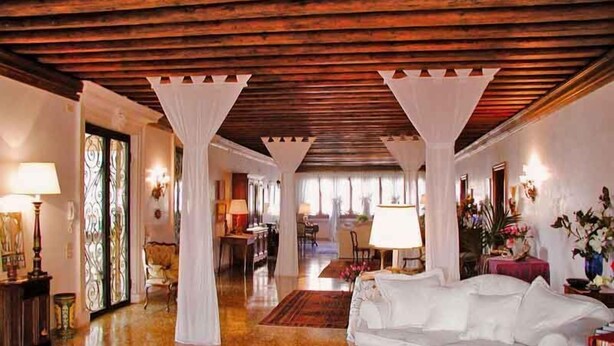 A spacious living room with a high ceiling, a white sofa, and a wooden floor. - At Home A Palazzo (Venice)